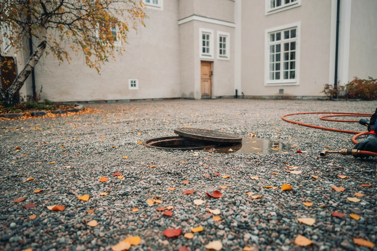 Illustration: händer i arbetshandskar för ner en spolslang i en brunn vid en villa i Gustavsberg